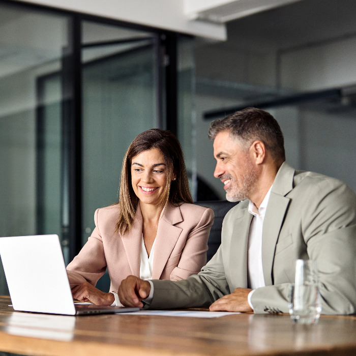 Man and woman smiling while looking at a computer