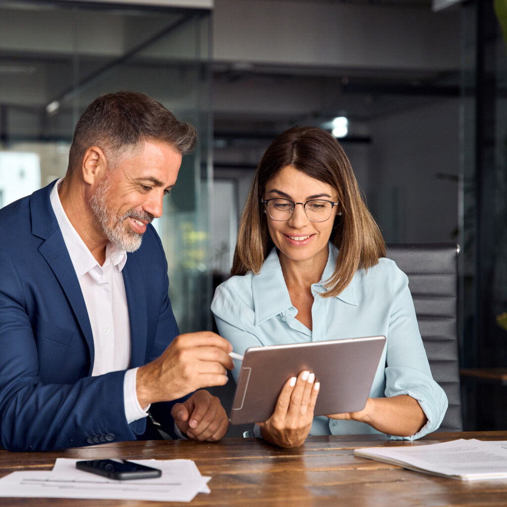 Man and woman smiling while and working together on a project on a tablet